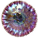 A purple lustre footed Northwood Carnival glass bowl with the 'Peacocks on a fence' pattern,