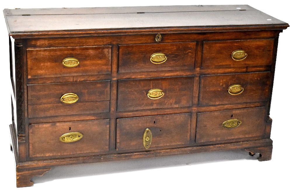 An early 19th century oak mule chest, lift-up top above six faux doors,