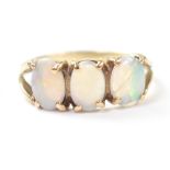 A 9ct gold three opal ring, the claw set white opals with hints of green and blue,