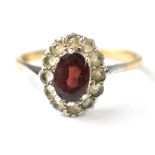 A 9ct gold fashion ring with central garnet within a border of white stones, size U, approx 2.3g.
