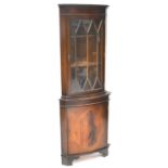 A reproduction mahogany floor-standing corner unit, with curved top rail above astragal glazed door,