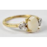 A 9ct yellow gold ring set with central opal with white cubic zirconium to shoulders, size L,