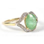 A 10ct yellow gold ring set with central emerald flanked by tiny white sapphires to shoulders,