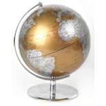 A modern terrestrial globe, the land shown in silver, the water in copper tones,