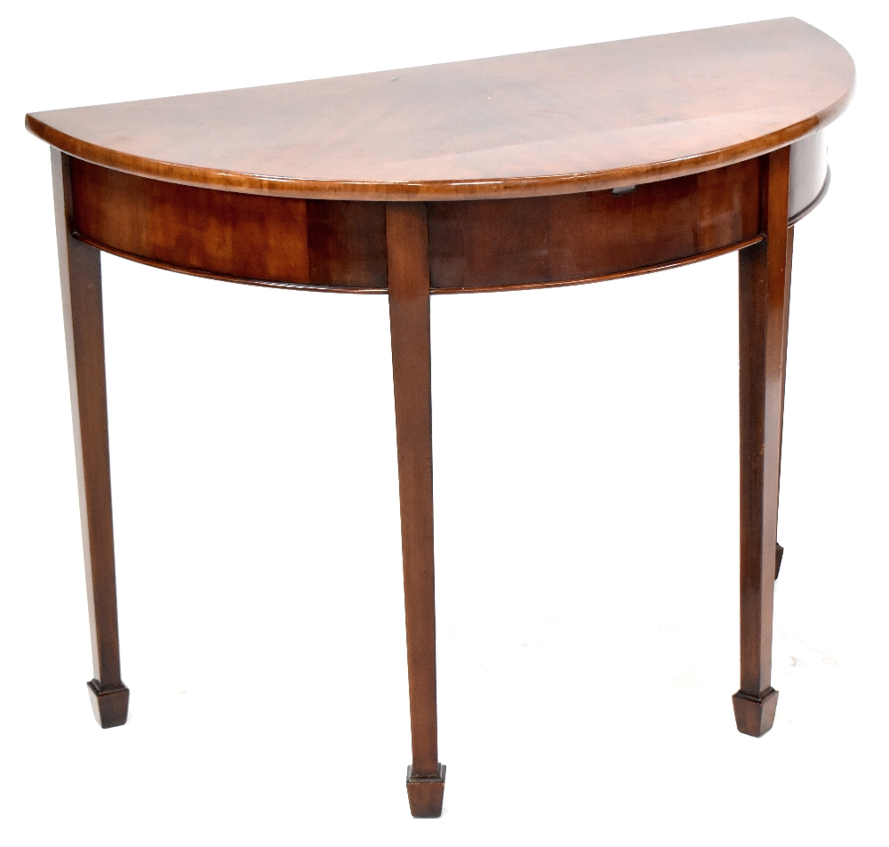 A 19th century flame mahogany demi-lune table, four tapering block supports to peg feet,