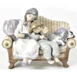 LLADRÓ; a large figural group of two sleepy children and dog seated on a sofa reading bedtime story,