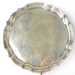 An Elizabeth II hallmarked silver waiter with shaped scalloped edge, raised on three scroll feet,