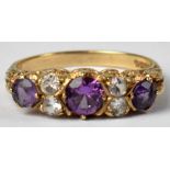 A 9ct gold ring set with three graduated amethysts interspersed with four diamonds, size R,