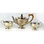 A George V hallmarked silver three-piece tea service comprising teapot with wooden handle and