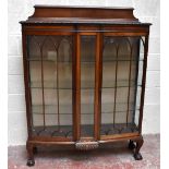 A 1920s walnut bowfront display cabinet with raised back above central bevelled glass panel