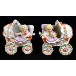 A pair of early 20th century German novelty figures of children in prams, with floral detailing,