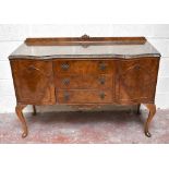 A 1950s walnut serpentine fronted sideboard, with three drawers flanked by two panelled cupboard