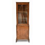 A 1950s burr walnut veneered display cabinet, the single glazed door enclosing two fixed shelves