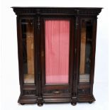 A 19th century French oak display cabinet, the carved cornice decorated a male and female mask,