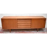 A mid-century teak sideboard with five central drawers flanked by two sliding cupboard doors, raised