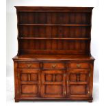 A reproduction oak dresser with plate rack back above three drawers and three panelled cupboard