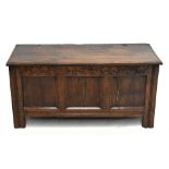An 18th century oak coffer, with carved detail above three panel front, raised on block feet,