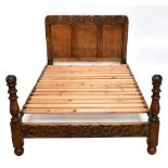 A modern carved oak double bedstead, the headboard with carved and panel detail, complete with slats