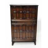 A Priory style drinks cabinet, the pair of panel doors enclosing mirrored back, above central drawer