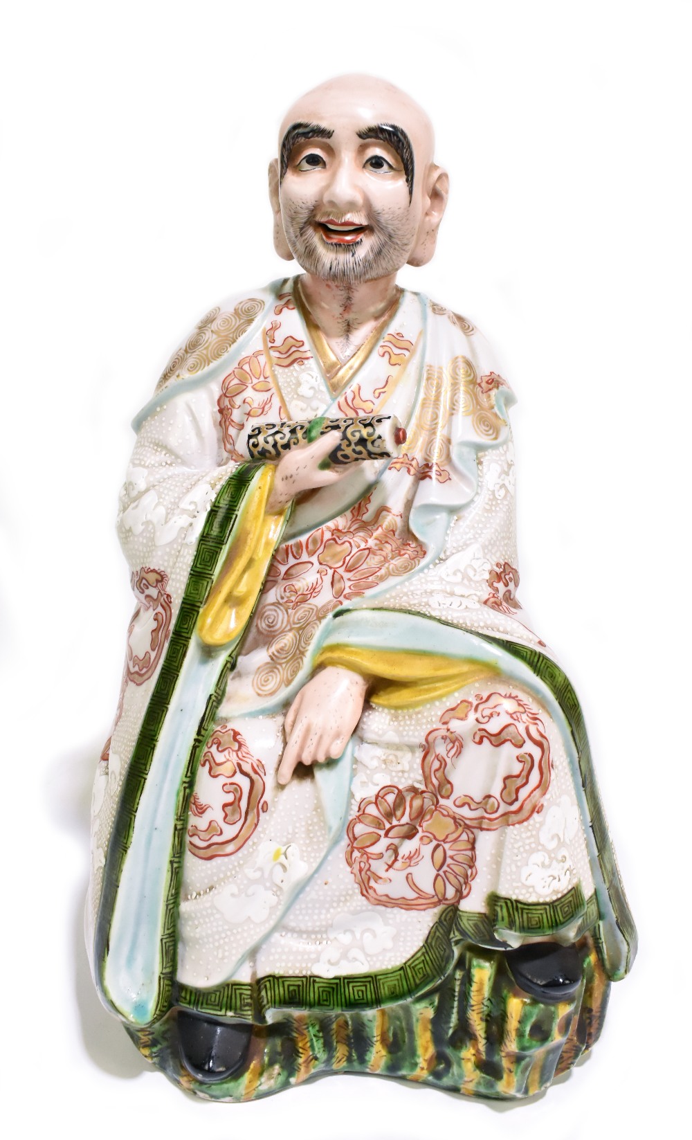 A late 19th century Chinese figure representing a seated scholar wearing a gown with relief and