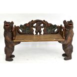 A reproduction Black Forest style bench, the central seat with carved detail depicting a bear