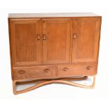 ERCOL; a rare elm and beech sideboard with three panel doors above two drawers, complete with