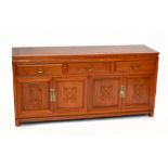 A Chinese carved hardwood sideboard with three short drawers and four panelled cupboard doors, on