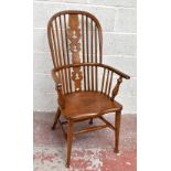 An early 20th century oak and ash, elm seated high back Windsor arm chair, with pierced central