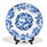 A late 19th century Kangxi style plate decorated in underglaze blue with floral panels, figures