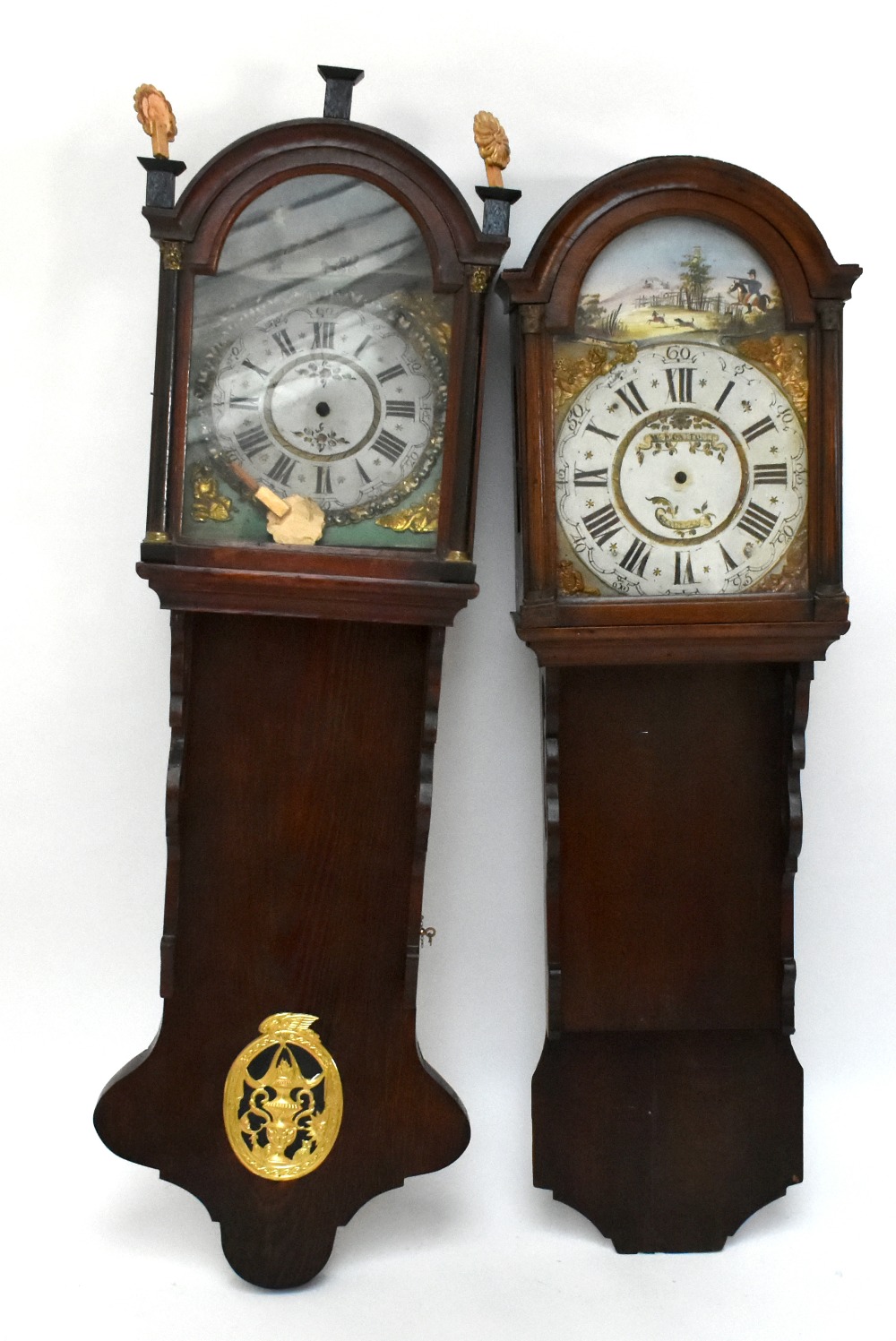 Two Continental wall clock cases, each with a domed hood and decorated dial, one in an oak case