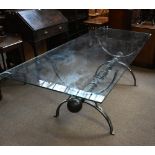 A modern glass top dining table, with cast iron frame with ‘X’ shaped end supports, height 76cm,