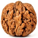 A Chinese carved walnut shell depicting figures and a dragon within leaves and flowers, height 5cm.