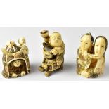 Three Japanese netsuke comprising a man holding up a mask,