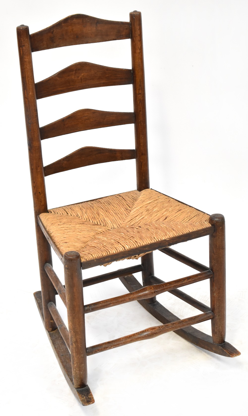 A 19th century rush seated country made ladder back rocking chair.