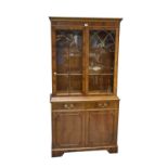 A reproduction yew wood bookcase with dentil moulded cornice above pair of glazed doors enclosing