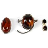 A hallmarked silver bangle set with large cabochon amber (af), a similar oval amber brooch,