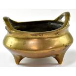 A Chinese bronze censer with loop handles, on tripod feet,