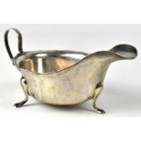 A George V hallmarked silver sauce boat with shaped rim and raised on three pad feet, Viners Ltd,