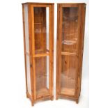 A pair of modern pine single-door display cabinets with three interior glass shelves and interior