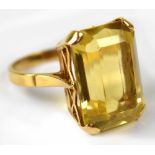 A yellow metal ring set with octagon cut citrine in a claw setting with open trellis design to