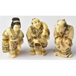 Three Japanese netsuke comprising a calligrapher holding a brush and scroll,