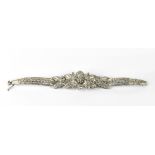 A white metal and diamond set articulated bracelet the centre in the form of a flower flanked by