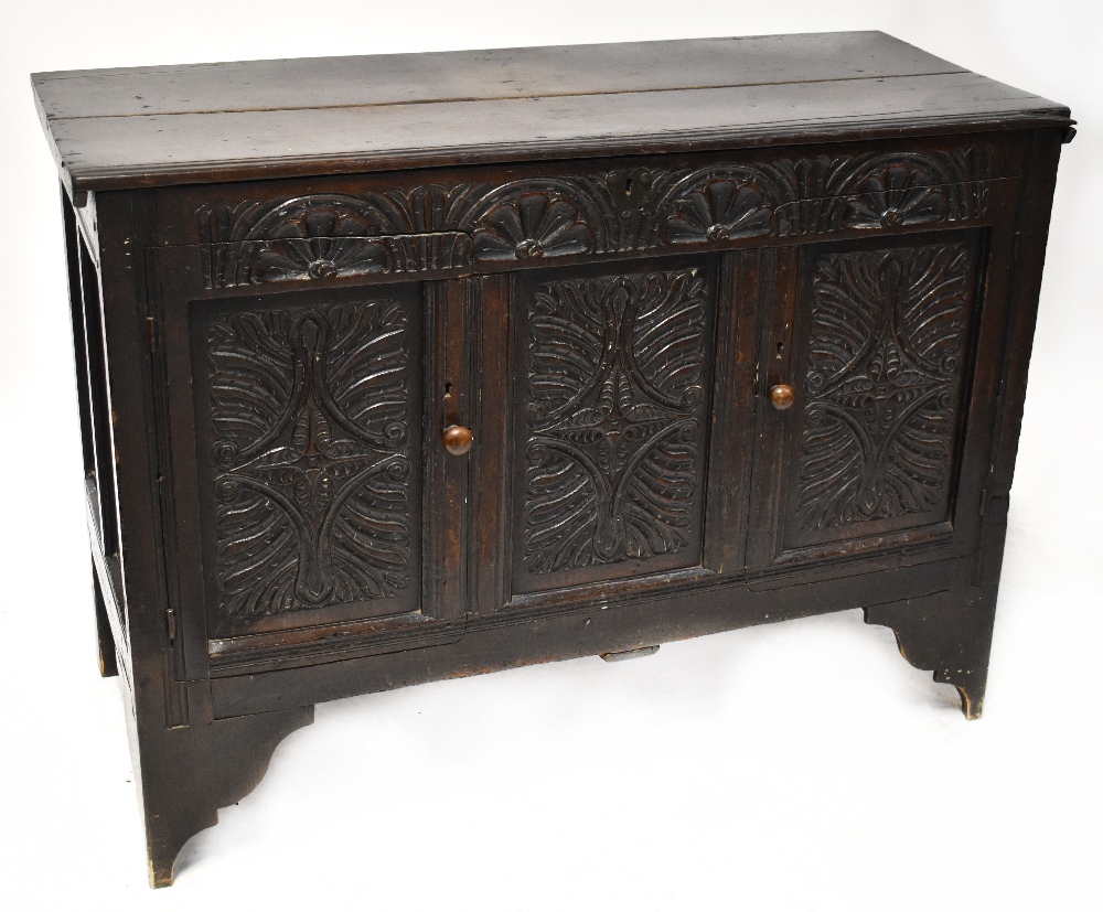 An 18th century oak mule chest with plank top above carved front,