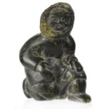 An Inuit soapstone carving of a figure dressed in a fur lined coat with mittens crouched on one