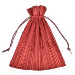 ISSEY MIYAKE; a red silk 'Pleats Please' drawstring bag with silver tone hardware drawstring ties