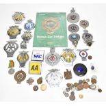 Nineteen various vintage car badges, including enamel examples, and a book relating to British car