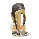 A vintage leather fleece lined flying helmet and pair of goggles stamped ‘Made in England’ (2).