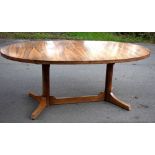 A 1970s rosewood extending dining table, with oval top on two circular column supports and