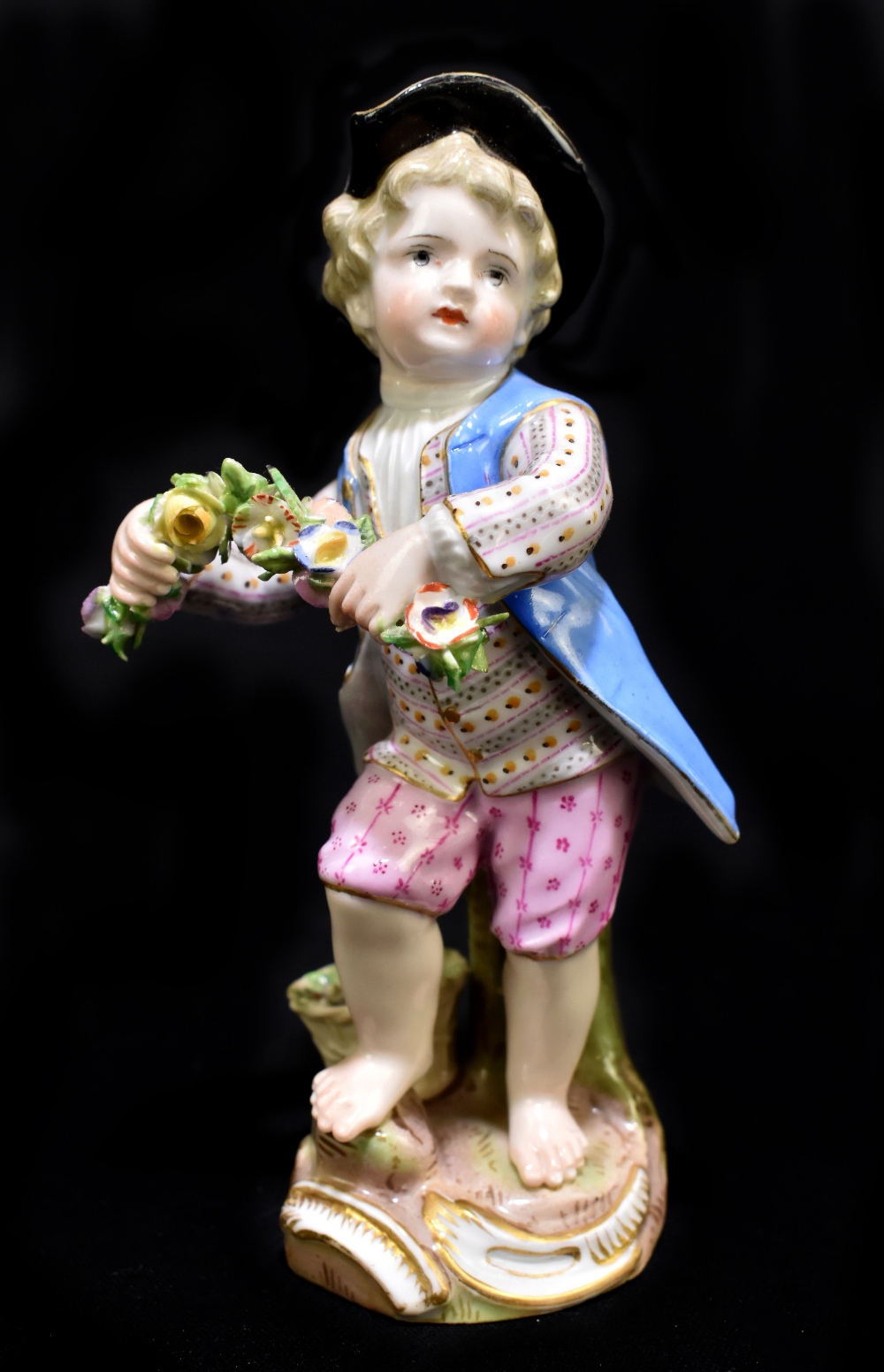 MEISSEN; a mid 19th century figure of a young child holding a garland of flowers, painted marks to