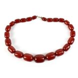 An early 20th century string of cherry amber graduated beads, length 46cm, the largest bead 30mm x